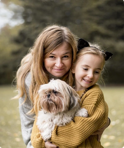 A mother and daughter hugging their dog